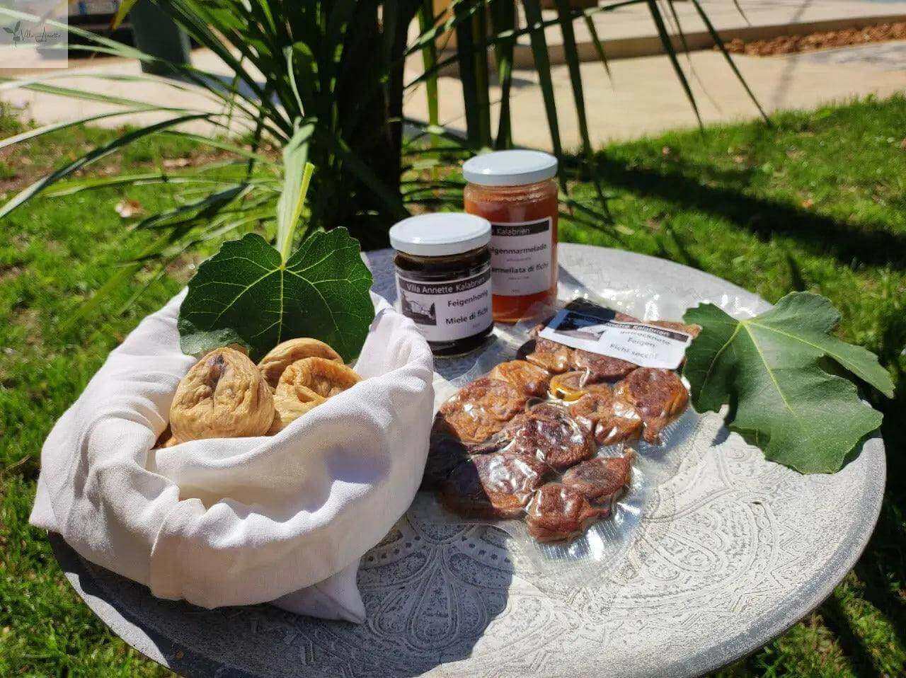 Dried figs 300g on a table with fig leaves, accompanied by jars of honey and fig products.