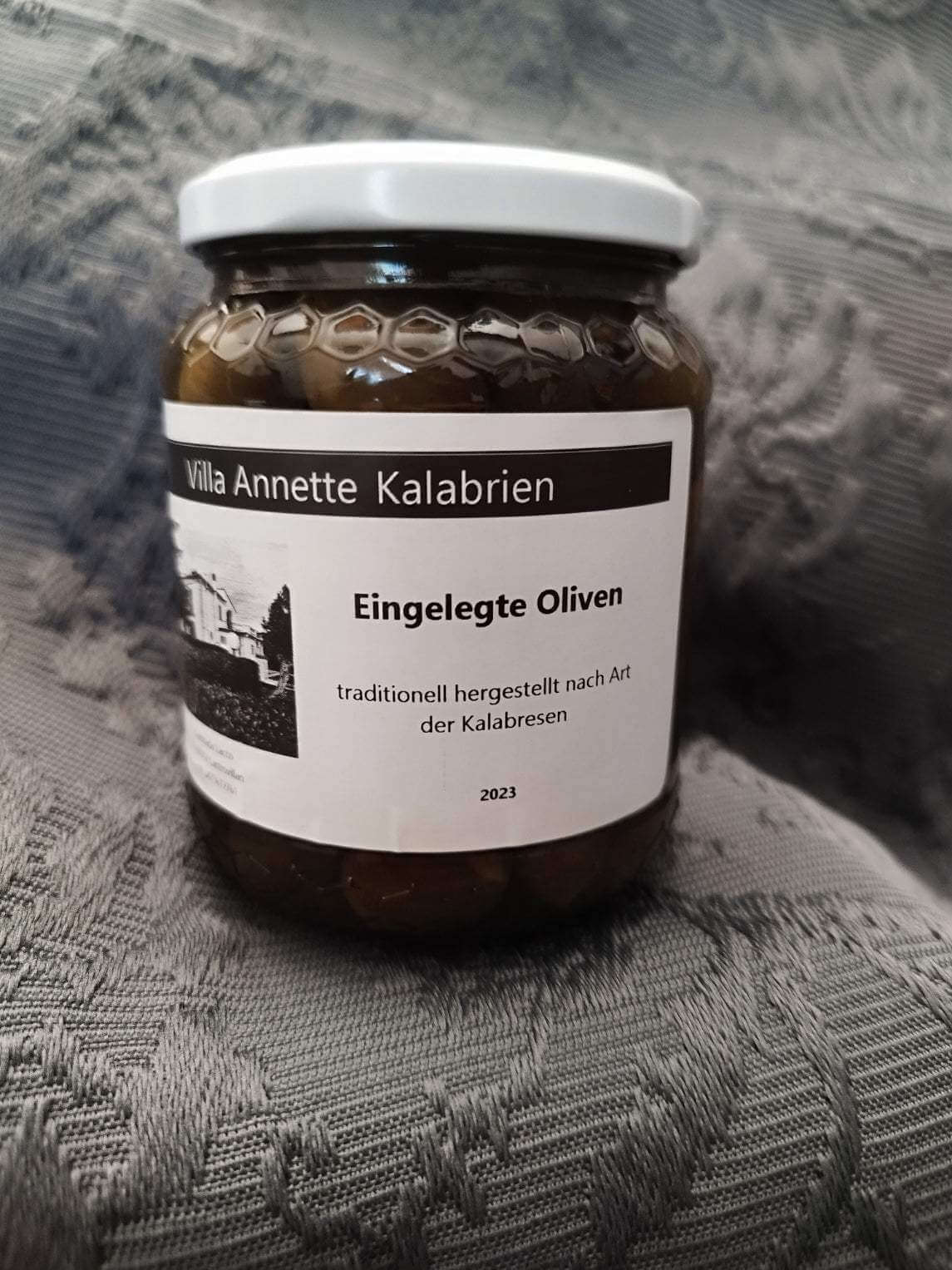 Jar of traditional Calabrian pickled olives with fennel and bay leaves.