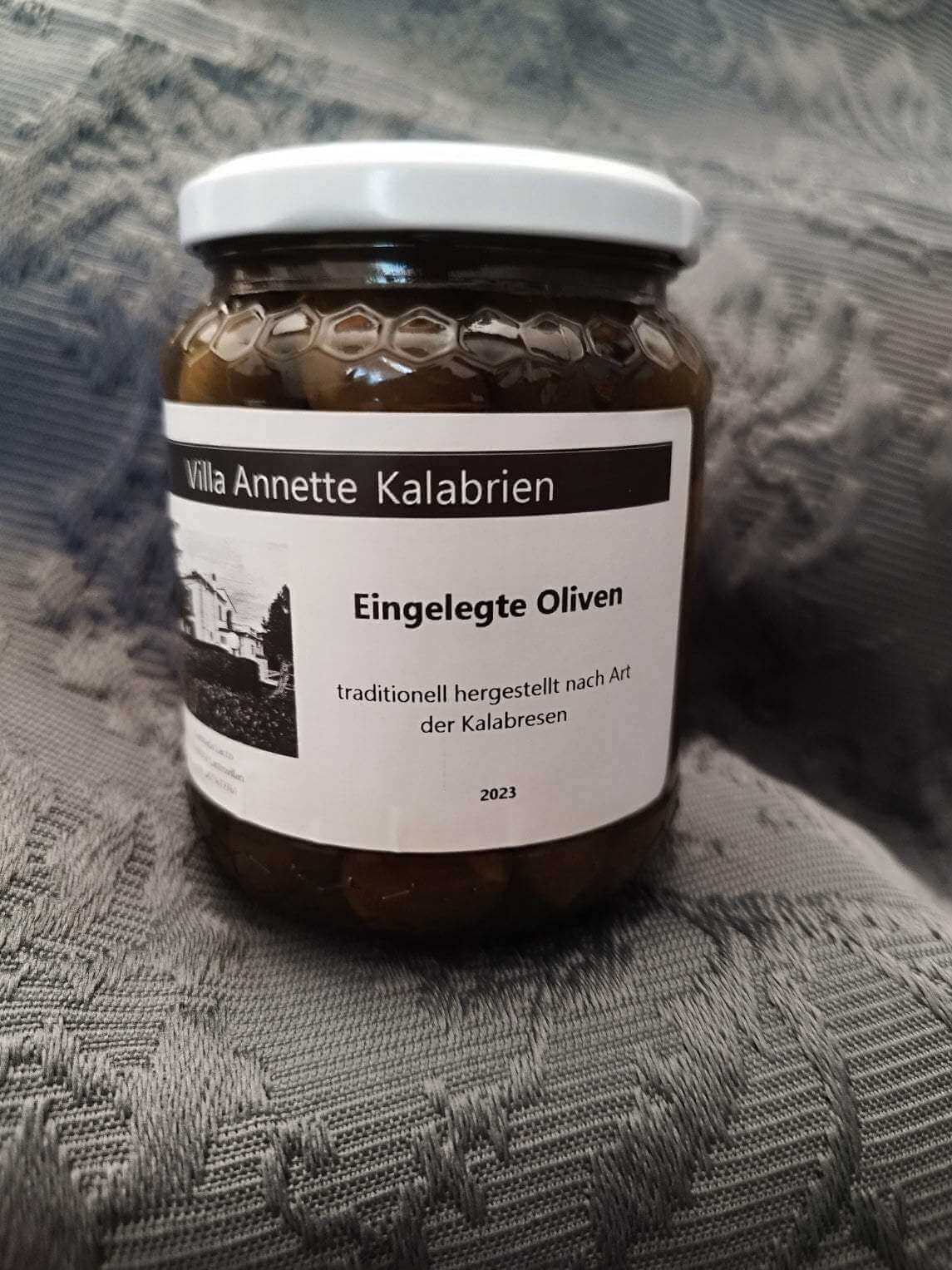 Jar of traditional Calabrian pickled olives with fennel and bay leaves.