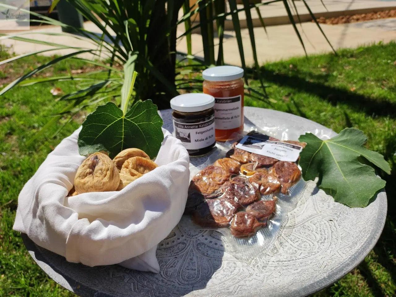 Dried figs 300g on a table with fig leaves, accompanied by jars of honey and fig products.