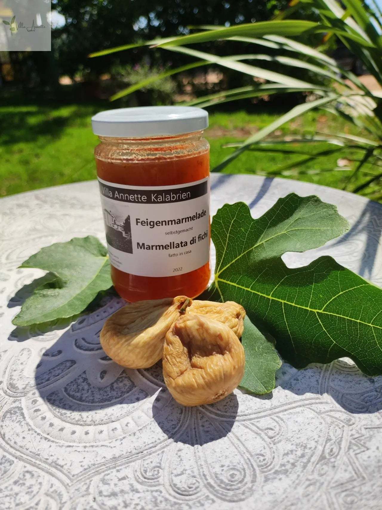 Feigenmarmelade aus Kalabrien im Glas auf Tisch mit Feigen und Blättern.